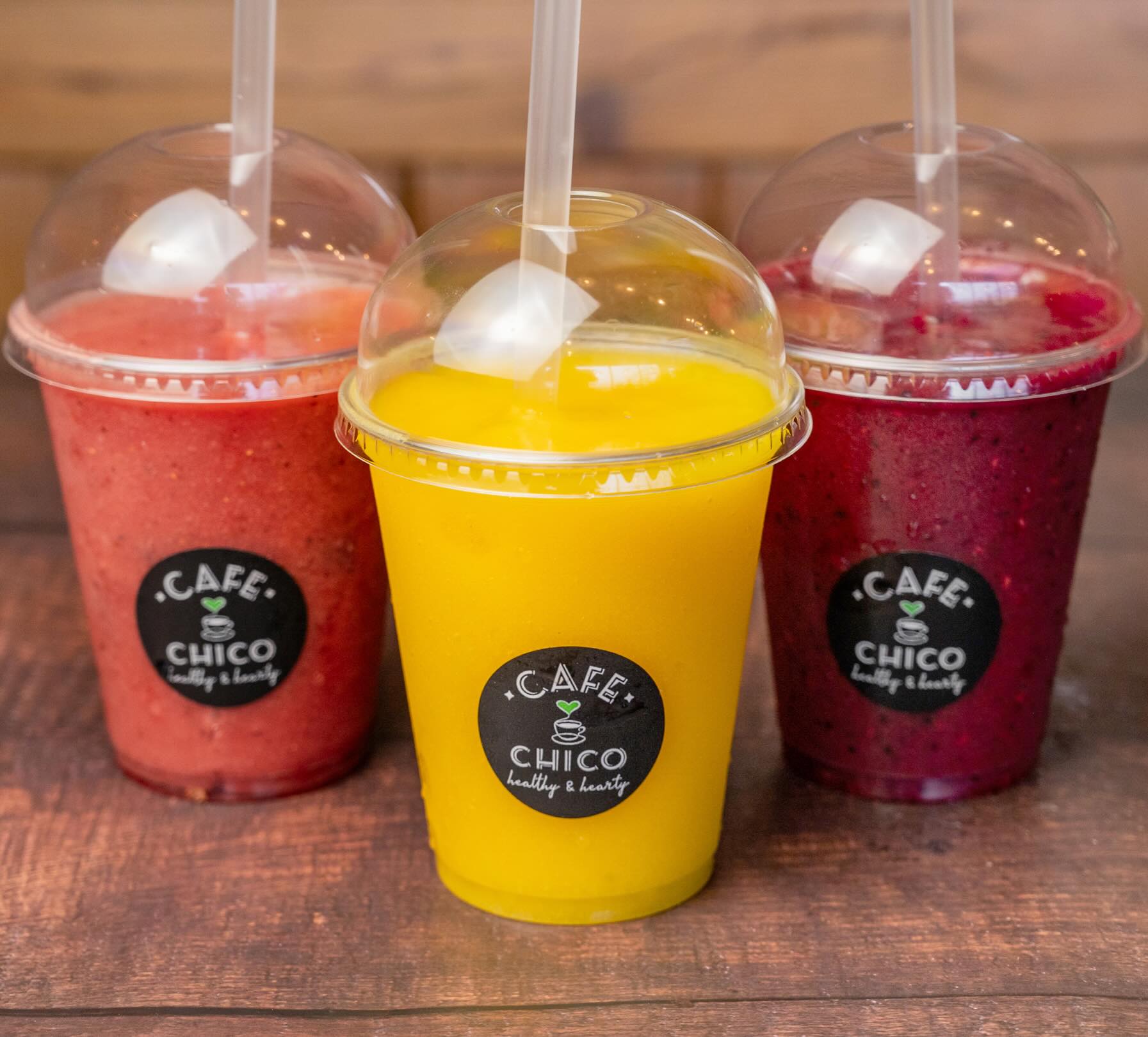Three colourful fruit smoothies in branded cups